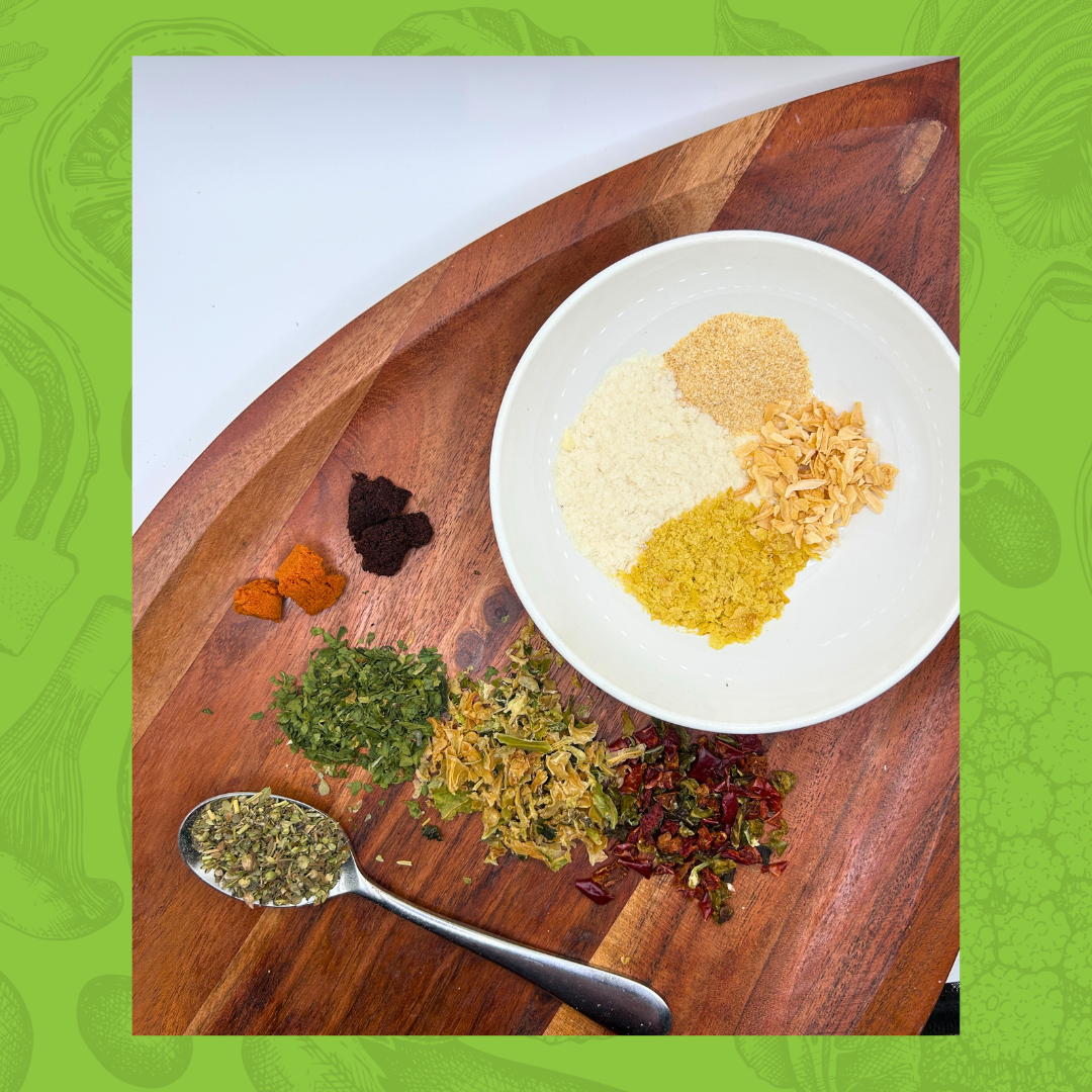 Assorted spices on a wooden board with a white plate and spoon.