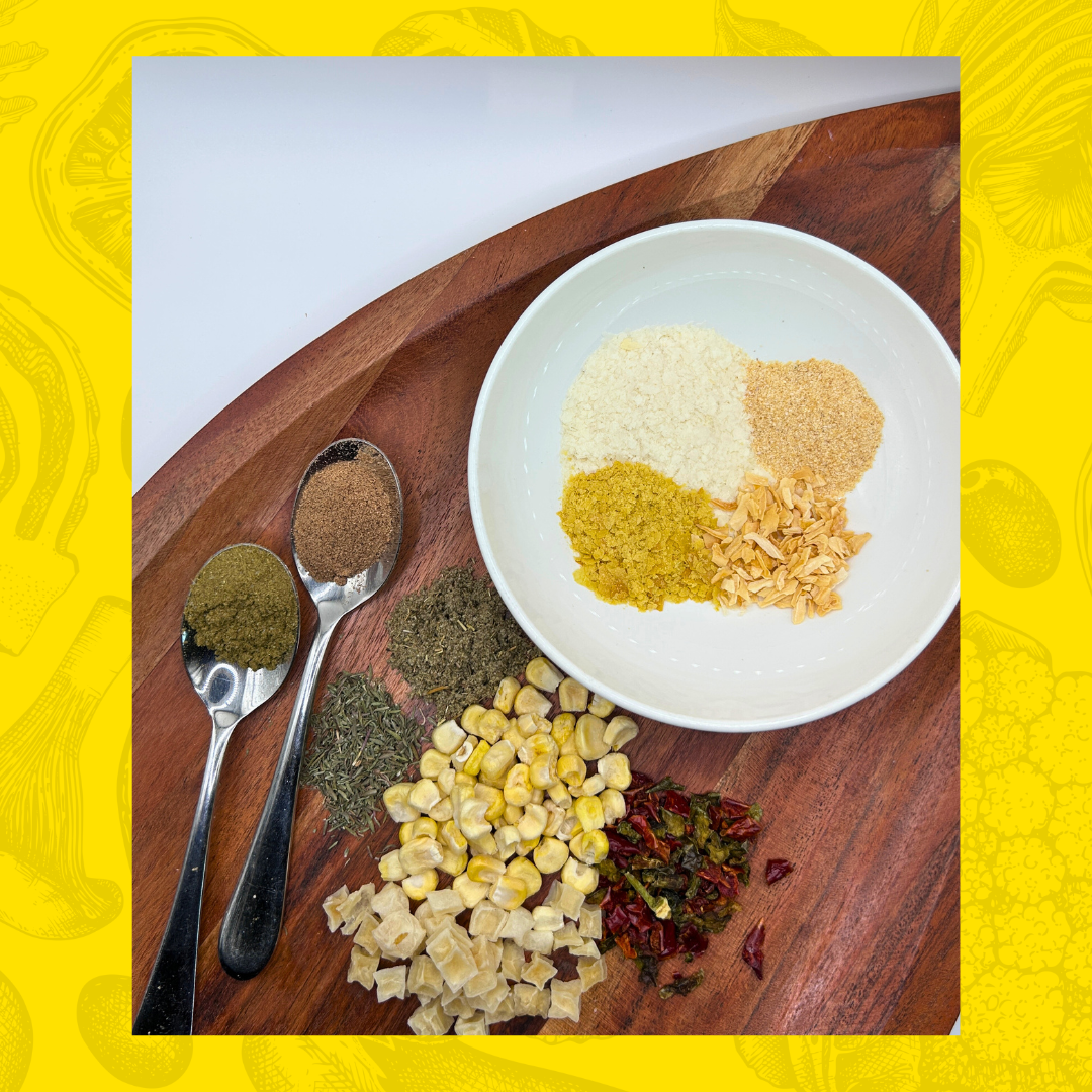 Spices and seasonings for Creamy Corn Chowder Soup on a wooden board with a white plate and spoons.